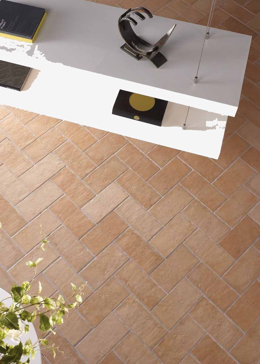 Estantería moderna blanca sobre suelo de baldosas de terracota en espiga, con planta y arte.