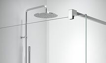 Cabezal de ducha cromado y mampara de ducha de cristal en un baño moderno.