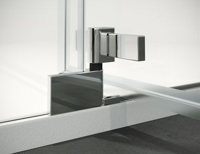 Primer plano de una bisagra de puerta de ducha cromada.