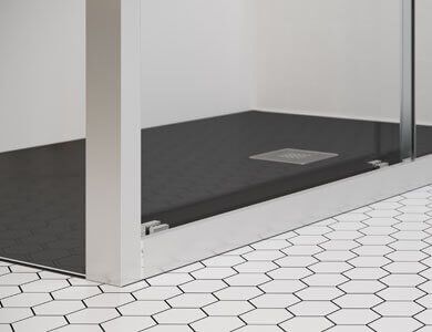 Base de ducha de color negro con paredes de cristal, molduras de metal y suelo de baldosas hexagonales blancas.