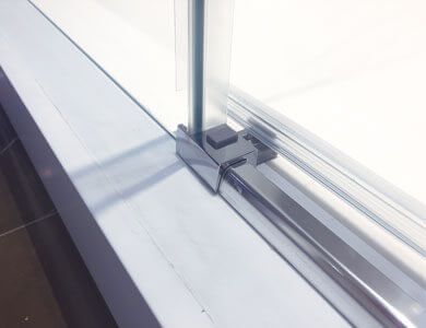 Puerta de ducha corrediza de vidrio con marco de metal que descansa sobre una repisa blanca.