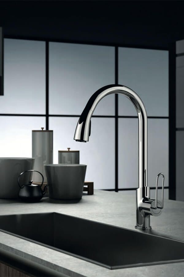 Grifo cromado sobre un fregadero negro en una cocina moderna con recipientes grises y una ventana grande.