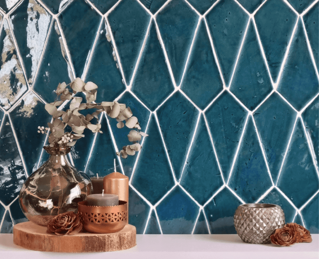 Azulejos de color verde azulado en forma de diamante con lechada blanca, decorados con jarrones y velas sobre una base de madera.