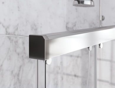 Herrajes plateados para puertas de ducha fijados a una pared revestida de mármol.