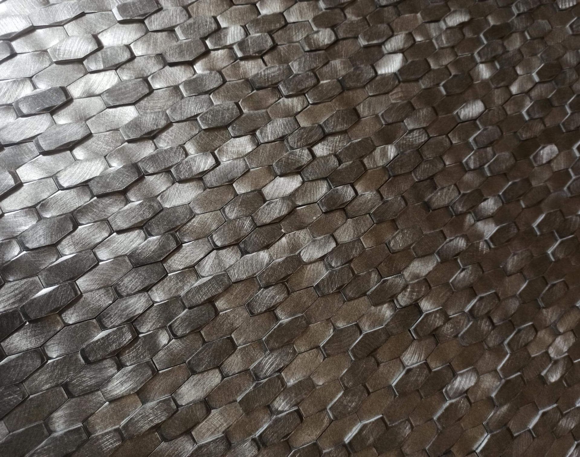 Primer plano de una superficie con un patrón repetitivo de formas hexagonales oscuras y texturizadas.