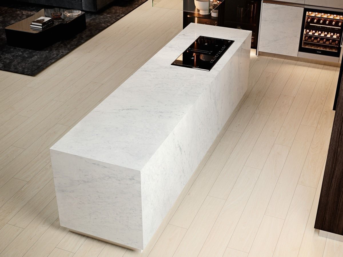 Isla de cocina de mármol blanco con estufa negra, en cocina moderna.