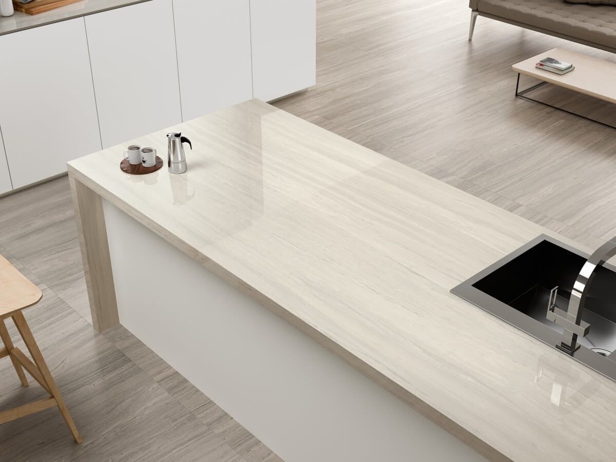 Isla de cocina con encimera de color claro, fregadero incorporado y gabinetes blancos.