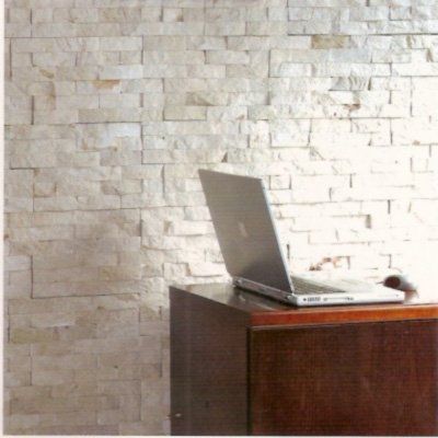 Computadora portátil sobre un escritorio de madera oscura frente a una pared de piedra texturizada de color claro.