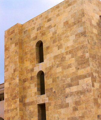 Edificio de piedra con dos ventanas arqueadas, de color tostado y marrón.