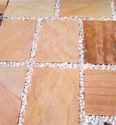 Pavimentos de piedra cuadrada de color tostado colocados en caminos de guijarros blancos.