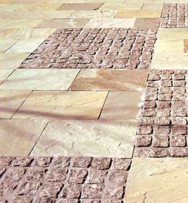 Pasarela pavimentada con grandes baldosas de piedra color tostado y secciones más pequeñas de ladrillo rojo.