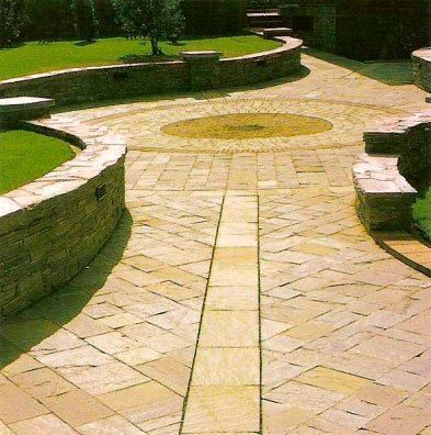 Patio de piedra con paredes curvas y diseño circular central.