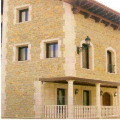 Edificio de piedra con fachada de color canela, molduras blancas y porche.