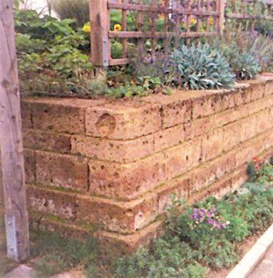Muro de contención de piedra con jardín, con plantas y enrejado de madera.