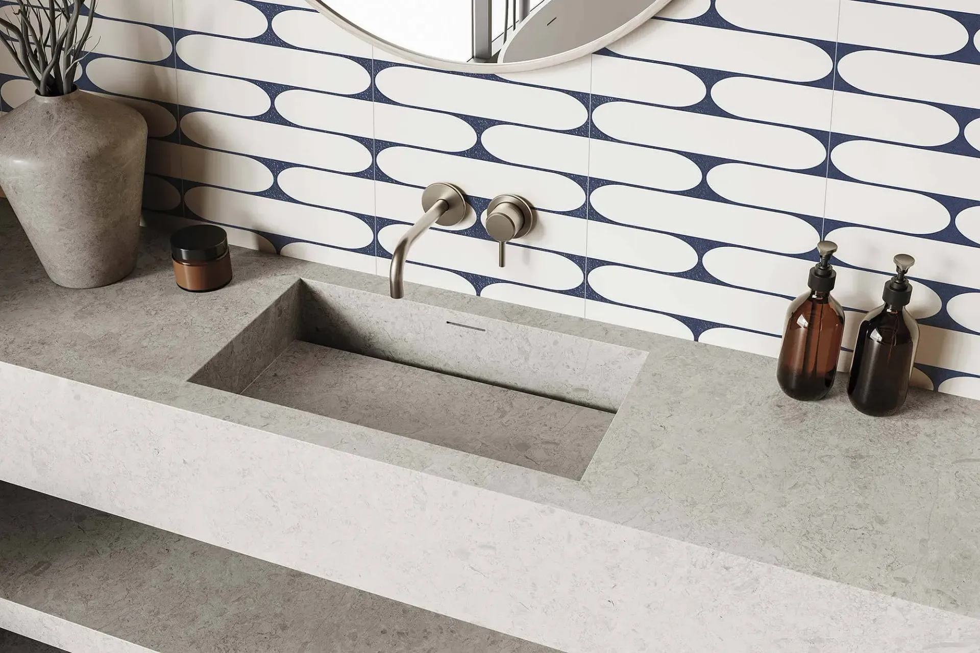 Baño con encimera de hormigón gris, lavabo rectangular incorporado y protector contra salpicaduras de azulejos con estampados azules y blancos.