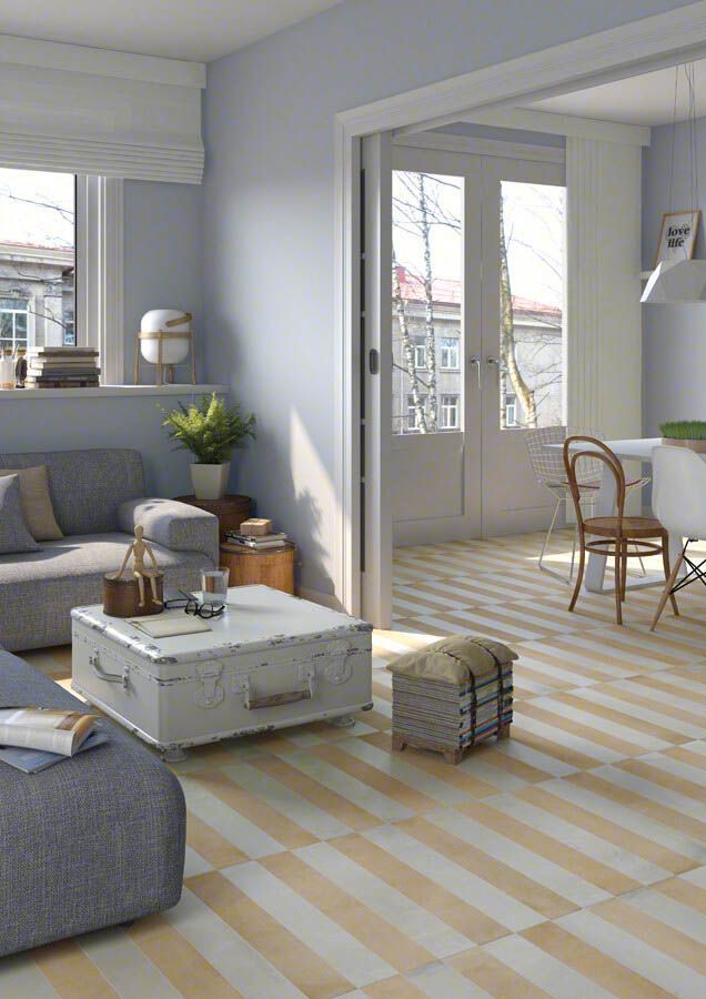 Sala de estar con paredes de color azul claro, sofá gris y pisos a rayas amarillas y blancas; puerta al comedor.