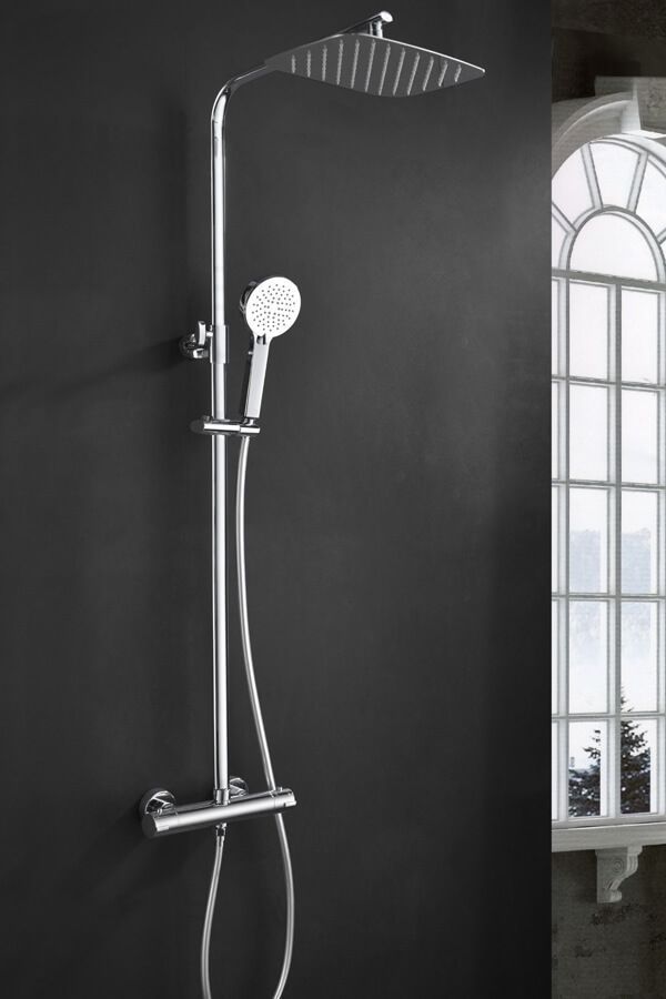 Artefacto de ducha cromado con cabezal de ducha tipo lluvia y ducha de mano contra una pared oscura.