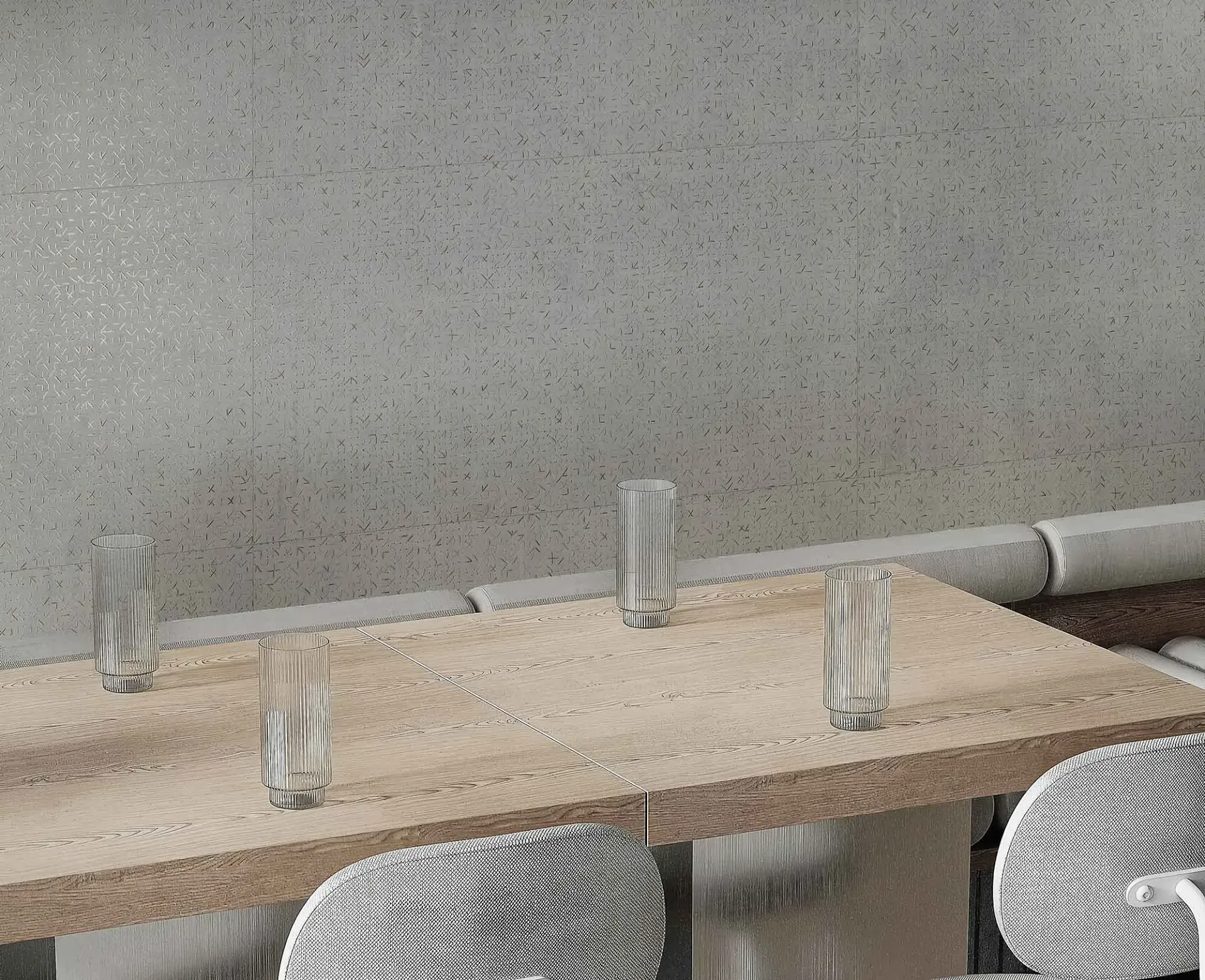 Mesa de madera con cuatro vasos y sillas decorativas. Pared gris texturizada al fondo.