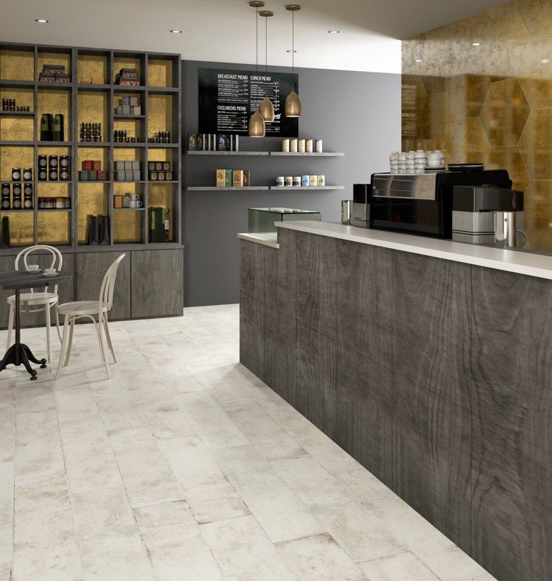 Interior de una cafetería con mostrador, estantes con productos y una pequeña zona de asientos.