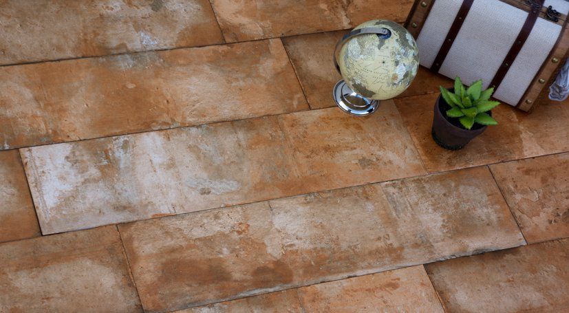 Azulejos de color marrón y blanco que parecen ladrillos, con un globo terráqueo, una maleta y una planta encima.