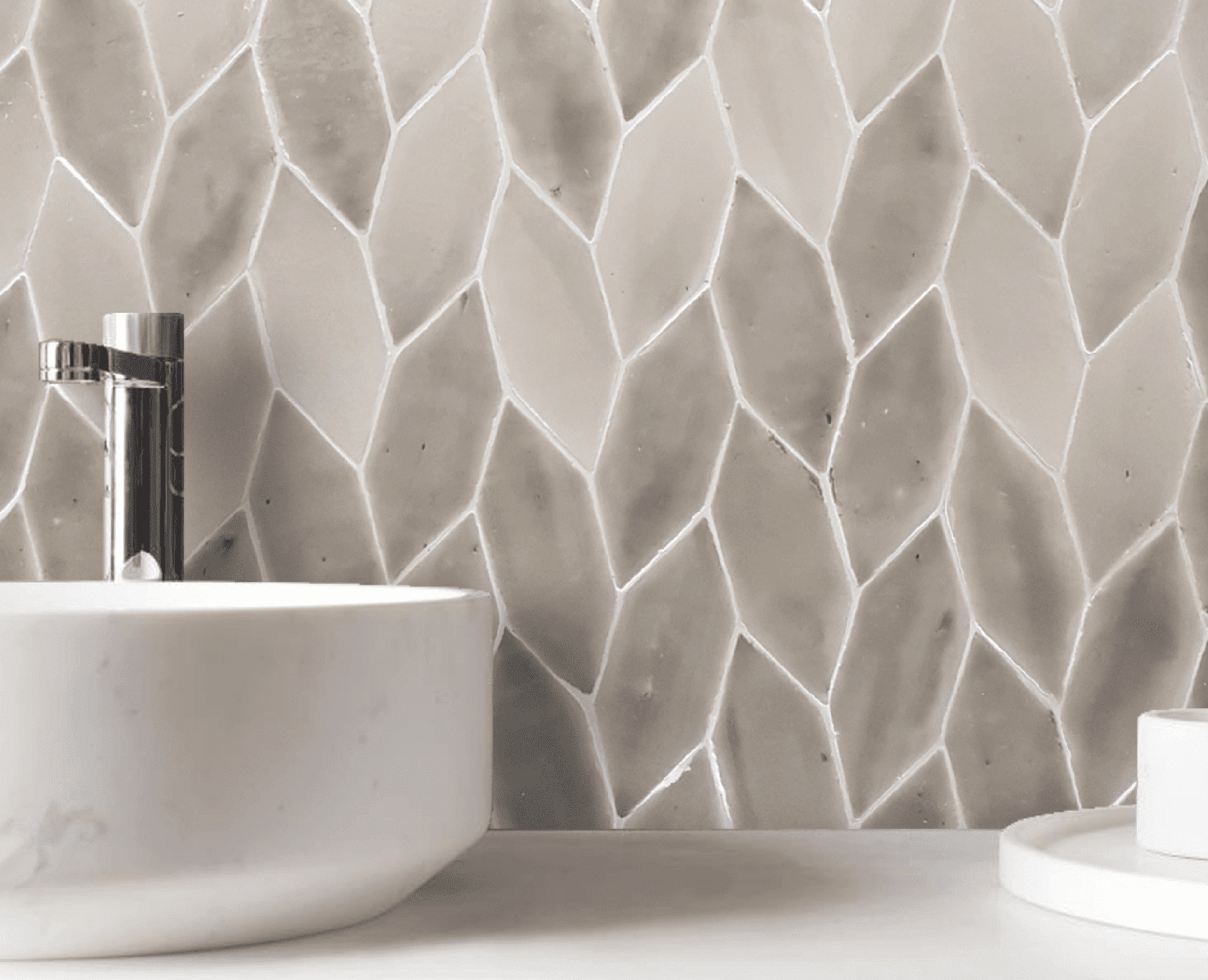 Baño con lavabo blanco, grifo plateado y salpicadero de azulejos de color marrón claro con forma de diamante.