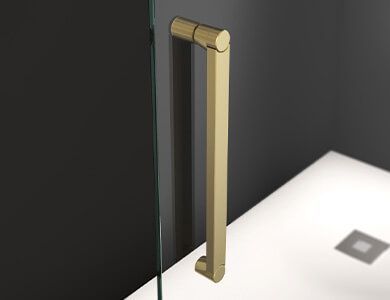 Manija de puerta de ducha dorada sobre panel de vidrio, dentro de una ducha.