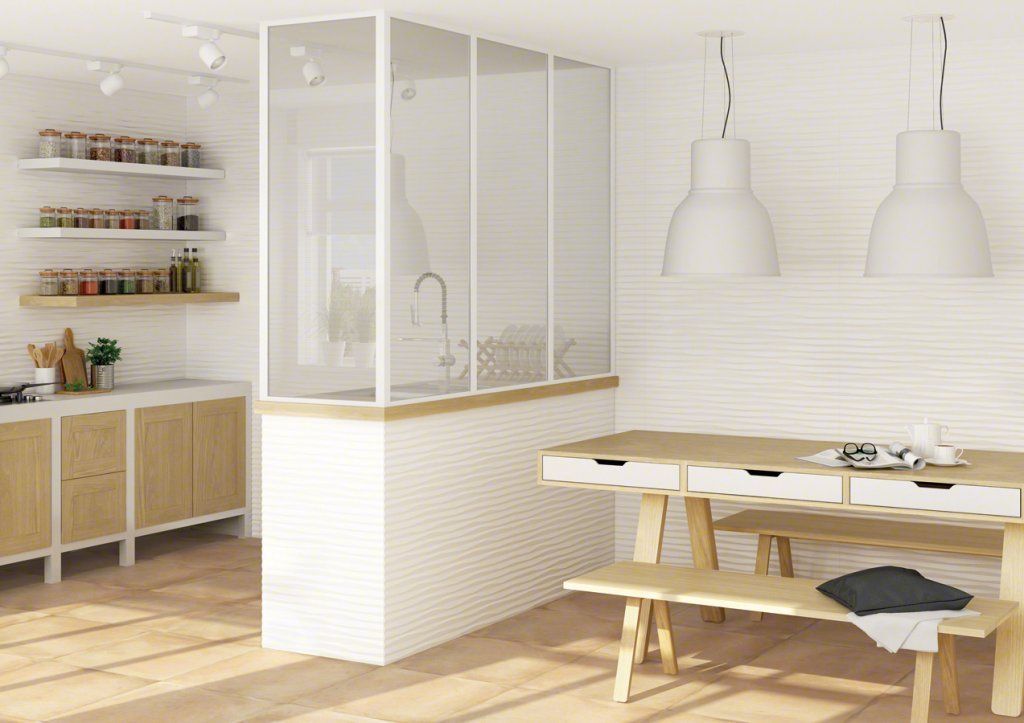 Cocina luminosa con fregadero con paredes de vidrio, gabinetes de madera, mesa de comedor y dos luces blancas colgantes.