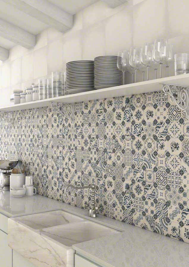 Cocina con salpicadero de azulejos estampados en azul y blanco, estanterías abiertas y fregadero blanco.