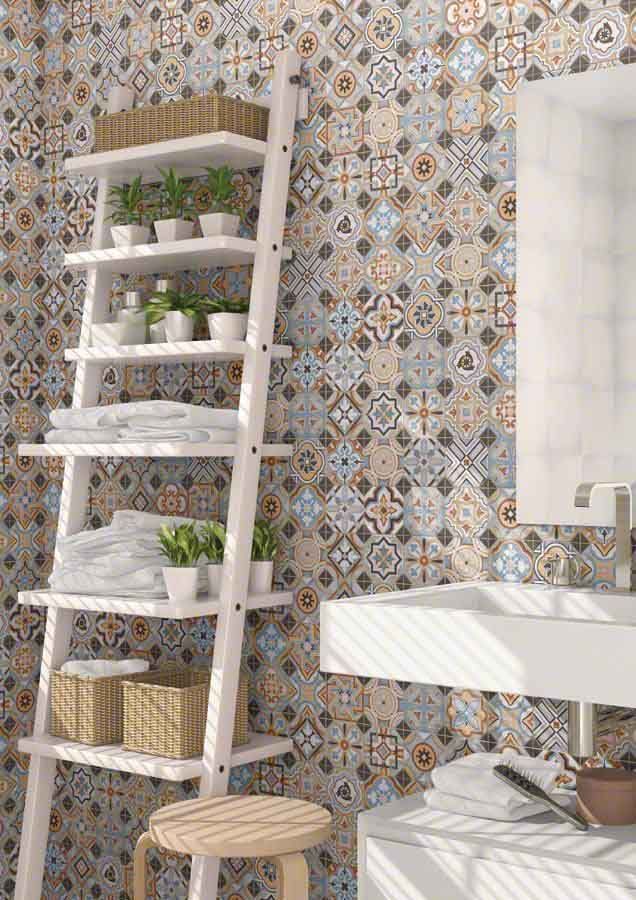 Baño con pared de azulejos estampados, estantería blanca con toallas, plantas y artículos de aseo. Incluye lavabo y taburete.