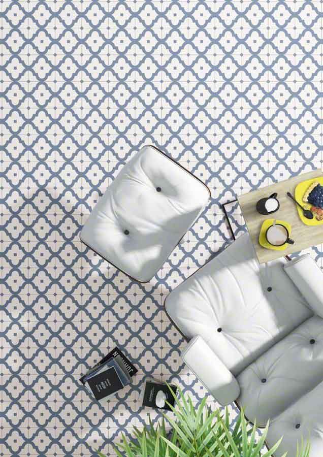 Sofá y silla de color blanco con mechones acolchados sobre suelo estampado en azul y blanco, mesa pequeña con comida.