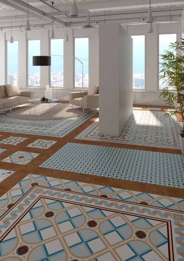 Espacio de estar de concepto abierto con suelo de baldosas estampadas, grandes ventanales y una pared parcialmente blanca. Se ven sofás y una planta.