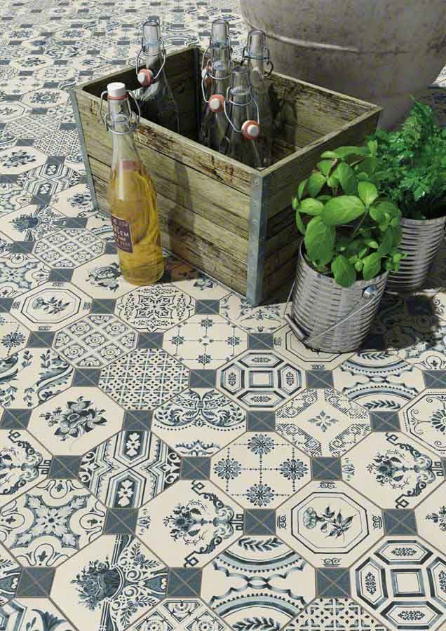 Suelo de baldosas con dibujos azules y blancos, con cajas de madera, botellas y plantas en macetas.