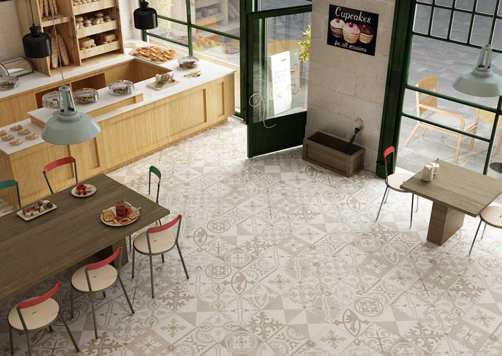 Interior de panadería con mostrador de madera, mesas y piso de baldosas estampadas.