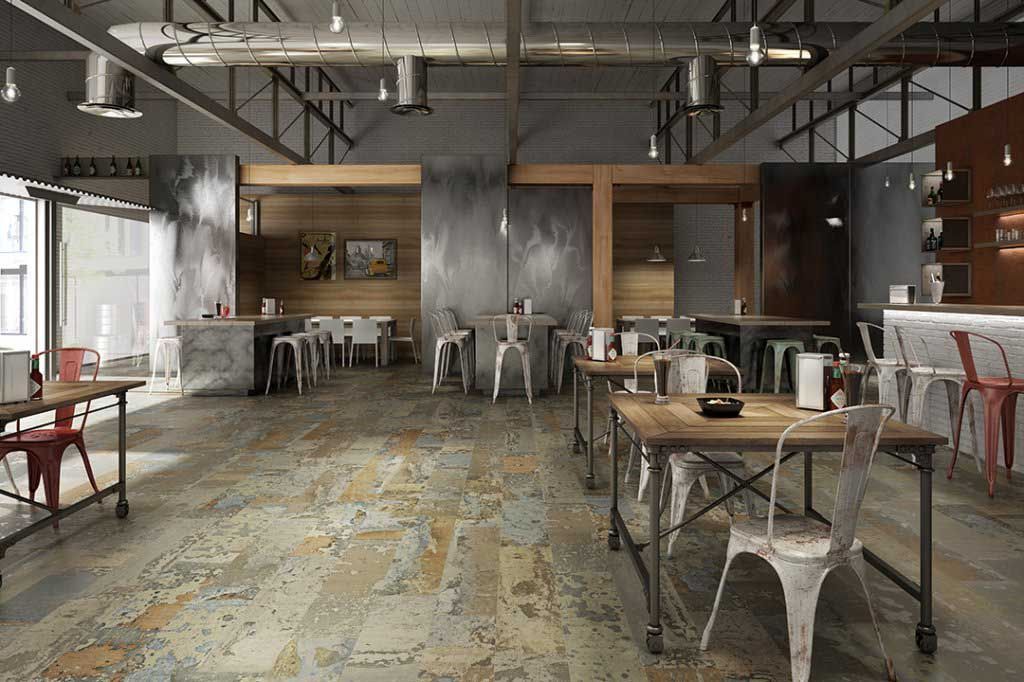 Interior de un restaurante rústico con mesas de madera y sillas de metal. Paredes de hormigón y techo abierto.