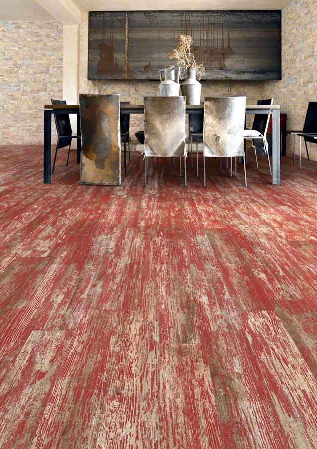 Comedor con suelo de madera envejecida en tonos rojos y beige y decoración rústica.