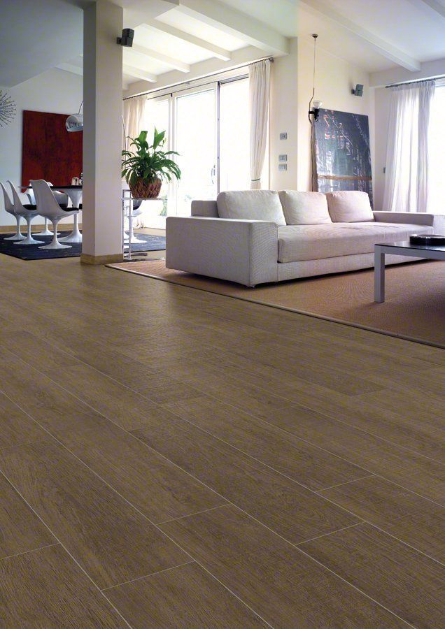 Suelo de madera en salón moderno con sofá blanco, alfombra y grandes ventanales.