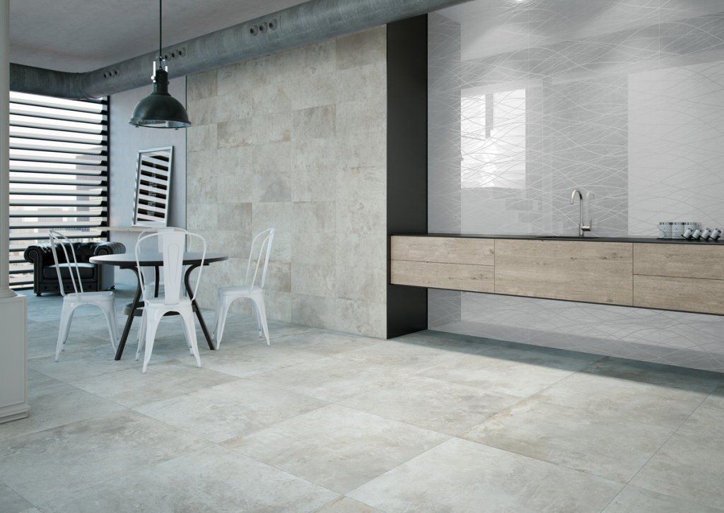 Cocina y comedor modernos con paredes y pisos imitación piedra, mesa con sillas blancas y lámpara colgante negra.