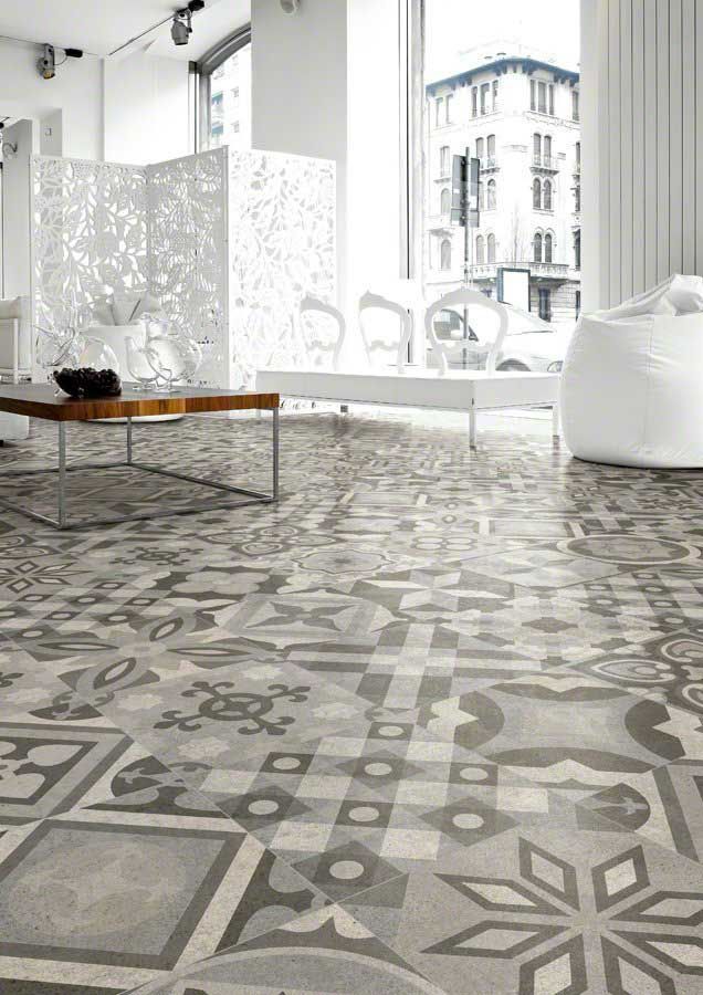 Piso de baldosas con dibujos grises en una habitación luminosa con muebles blancos y una ventana grande.