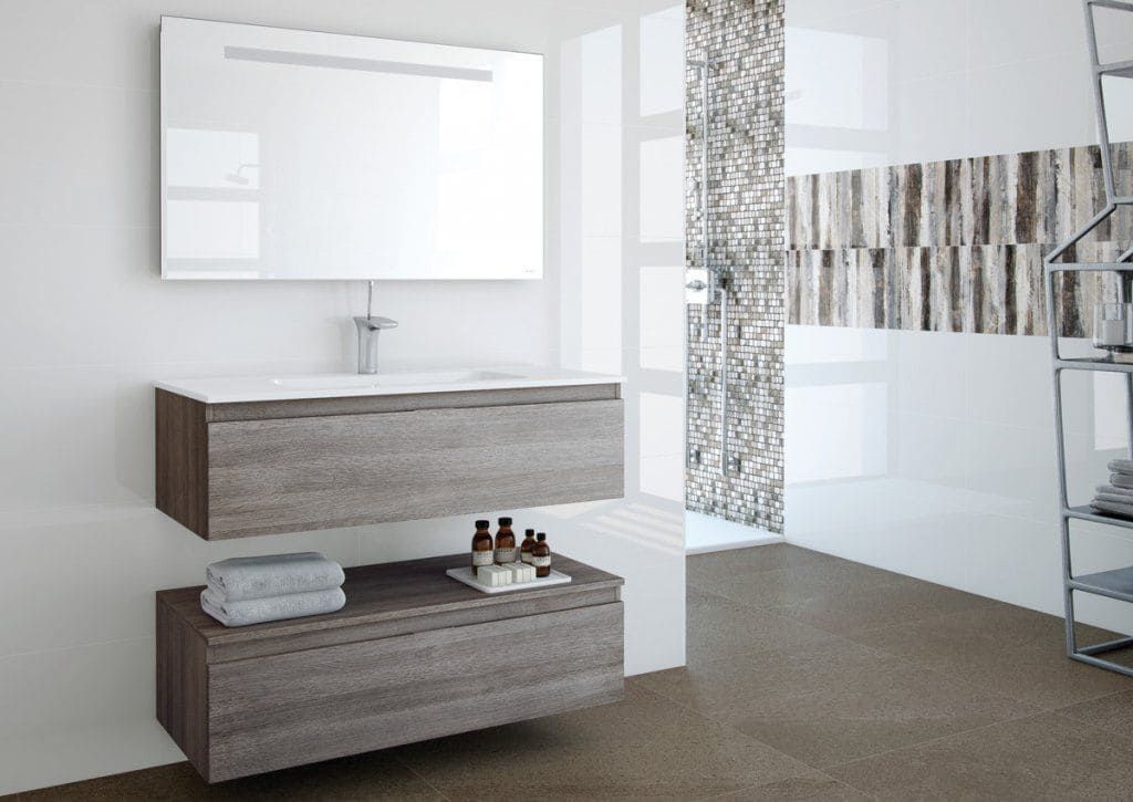 Baño moderno con tocador flotante y espejo; gabinetes con apariencia de piedra, pared blanca, piso marrón y azulejos decorativos.