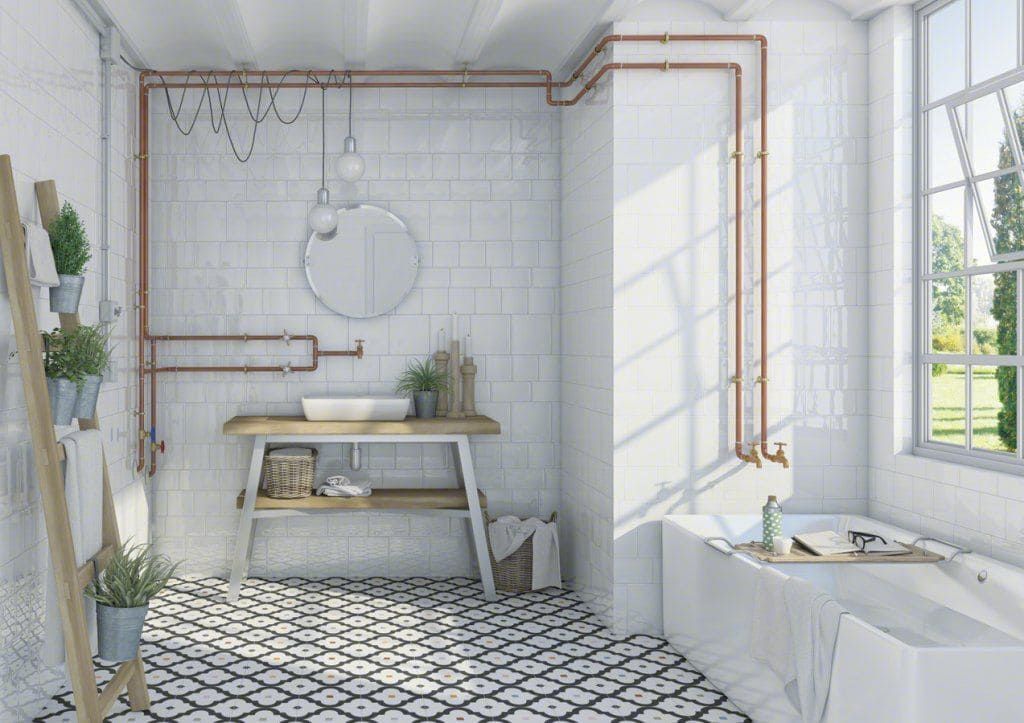Baño con paredes de azulejos blancos, tuberías de cobre, tocador de madera y piso estampado.