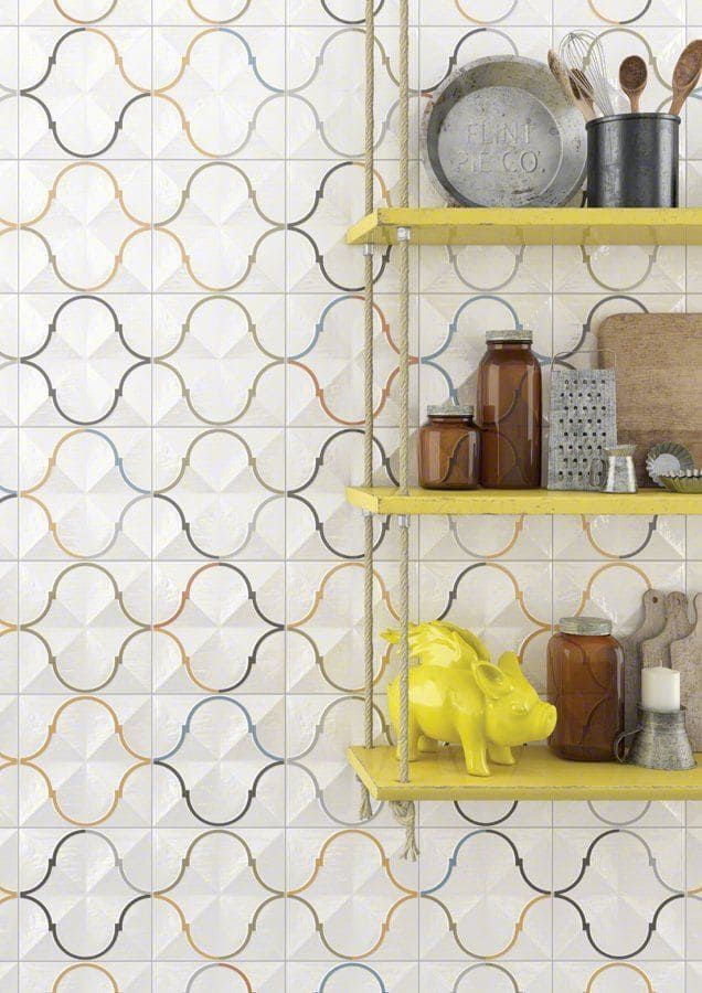Pared de azulejos con dibujos blancos y estantes amarillos que contienen artículos de cocina.