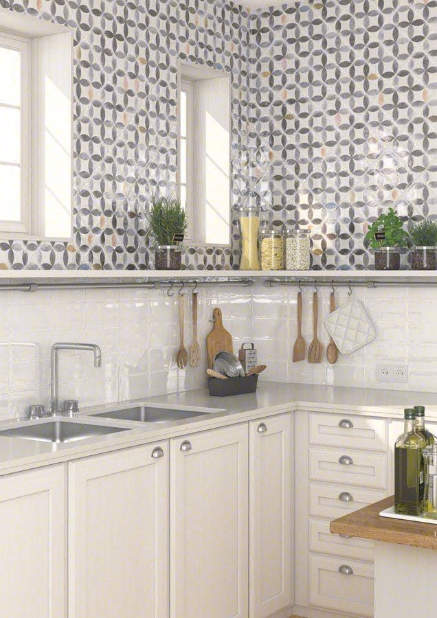 Cocina con gabinetes blancos, salpicadero de azulejos estampados y fregadero de acero inoxidable.