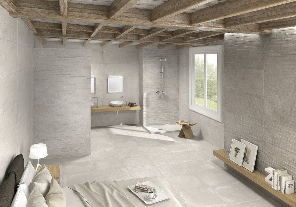 Baño espacioso y luminoso con vigas de madera a la vista, paredes de piedra clara y una gran ventana.