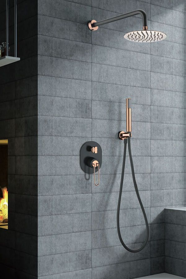 Moderno artefacto de ducha en baño alicatado; tonos negro y oro rosa.
