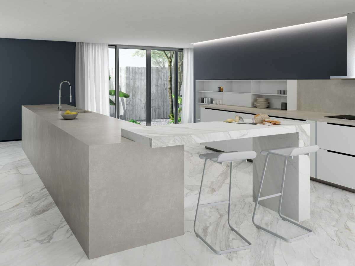 Cocina moderna con isla grande, colores neutros, suelo de mármol y taburetes. Pared azul oscuro con puerta corredera.