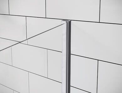 Pared de azulejos blancos con borde metálico vertical, que muestra líneas que se entrecruzan.