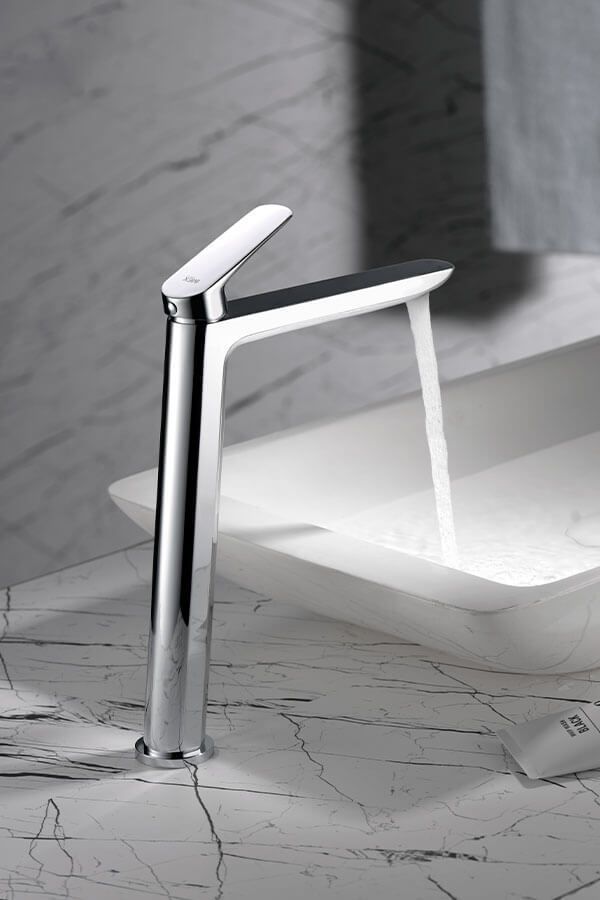 Grifo cromado que vierte agua en un fregadero blanco, colocado sobre una encimera de mármol.