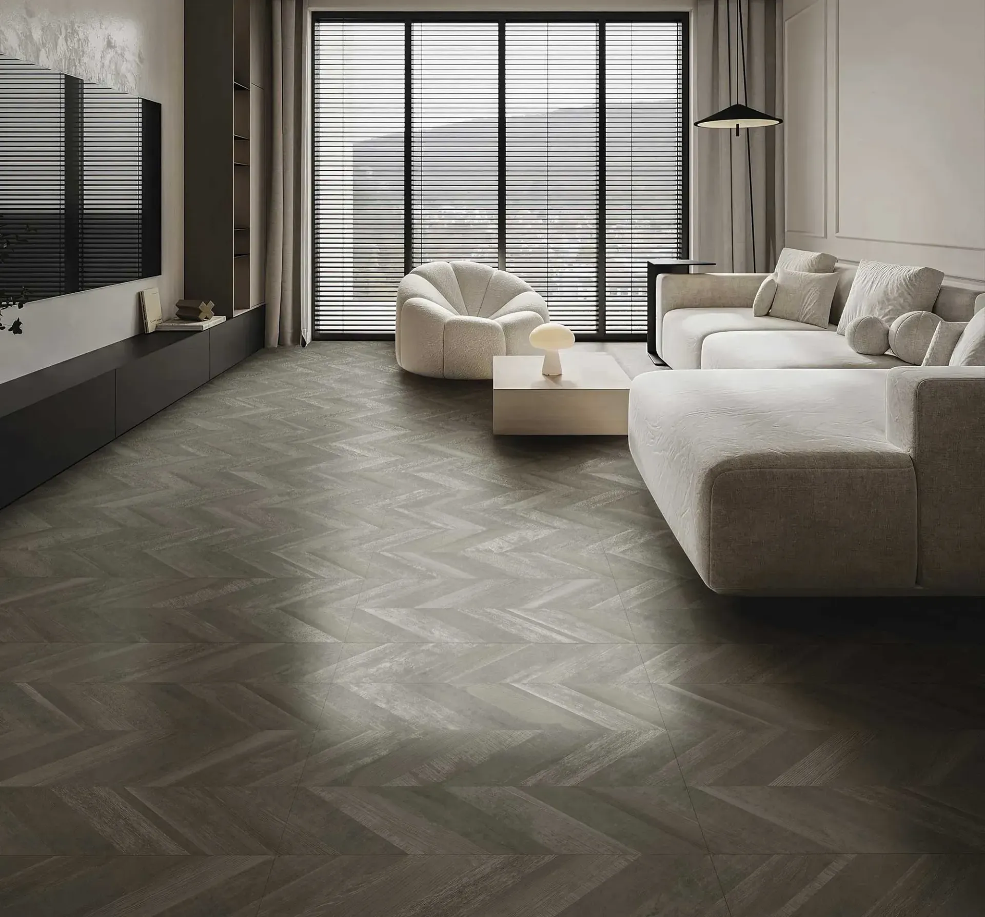 Sala de estar con suelo de madera en espiga, sofá, sillón y mesa de centro de color claro. Gran ventanal con persianas.