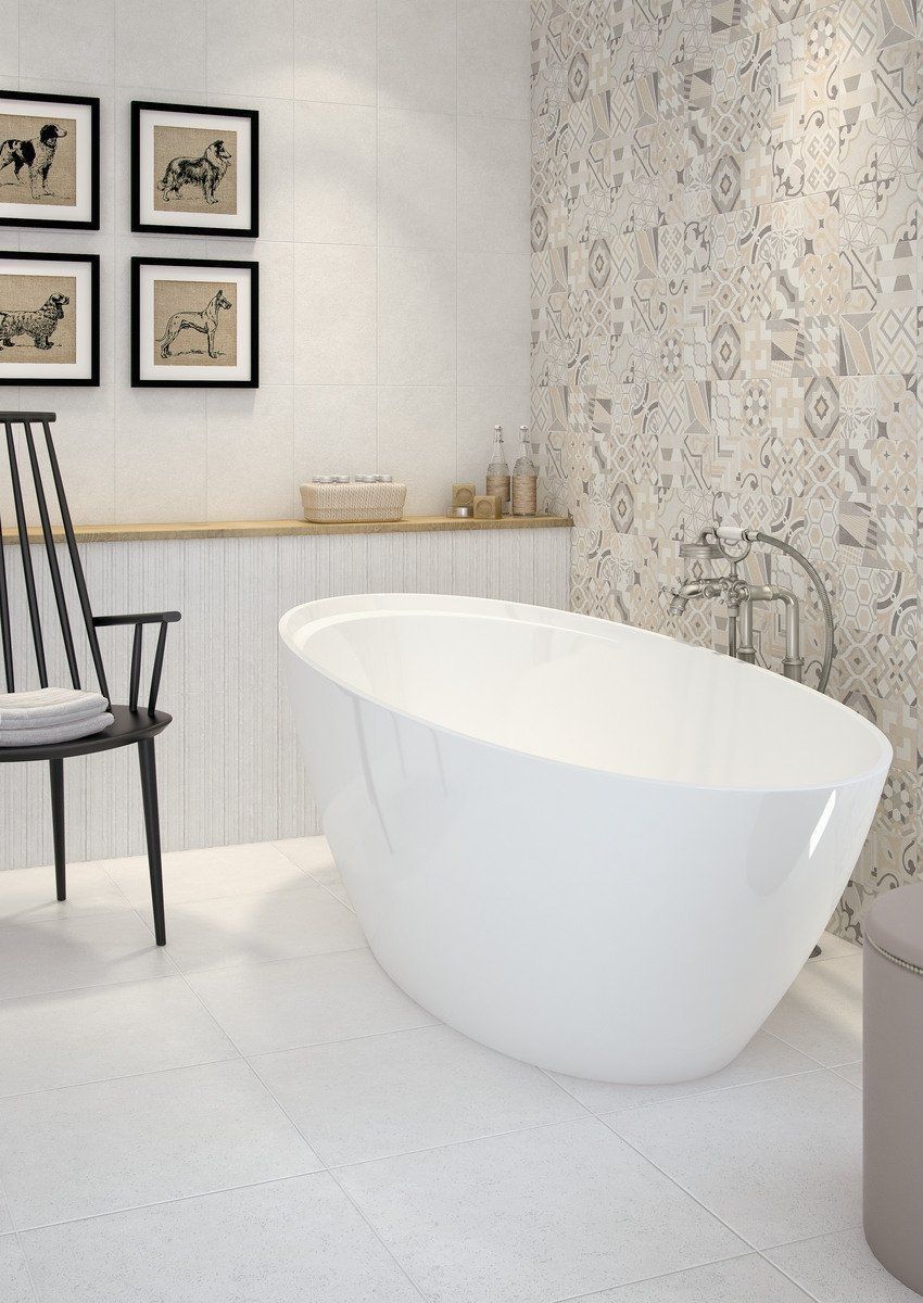 Baño moderno blanco con bañera independiente, obras de arte enmarcadas y azulejos estampados.