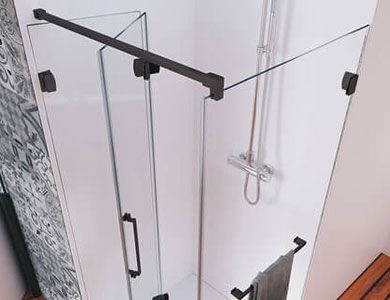 Mampara de ducha de cristal con herrajes negros en un baño.